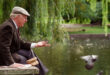 Elderly man feeding pigeons in park
