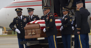 Marine in casket being lifted from jet plane