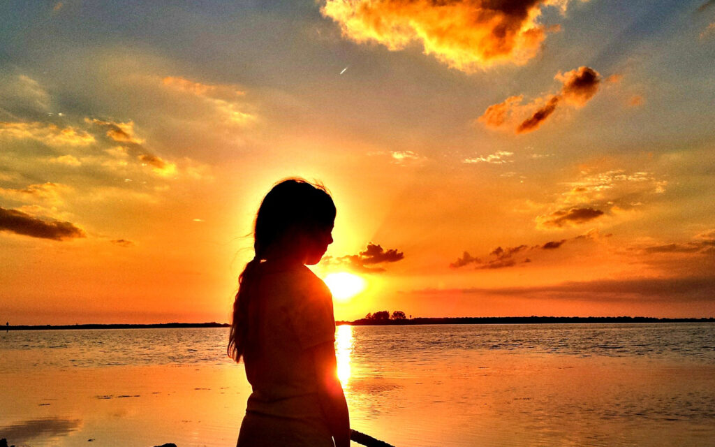 girl standing in front of sunset