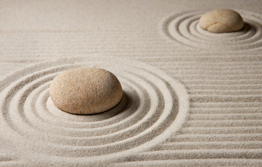 two stones on a beach of smooth, designed sand