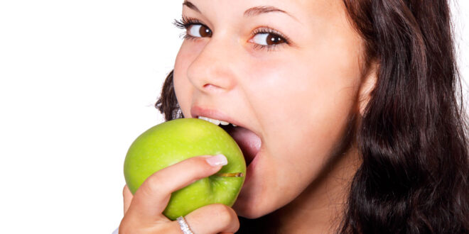 young girl eats green apple