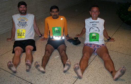 3 barefoot runners sitting after race
