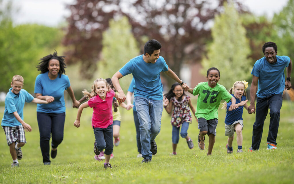 group of kids running with encouragement from adult