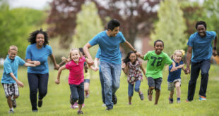 group of kids running with encouragement from adult