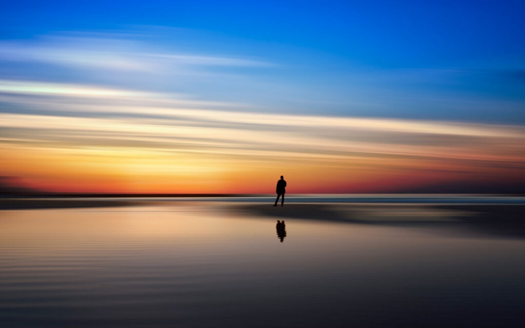 man at shoreline at sunset