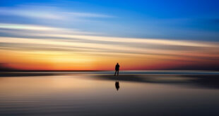 man at shoreline at sunset